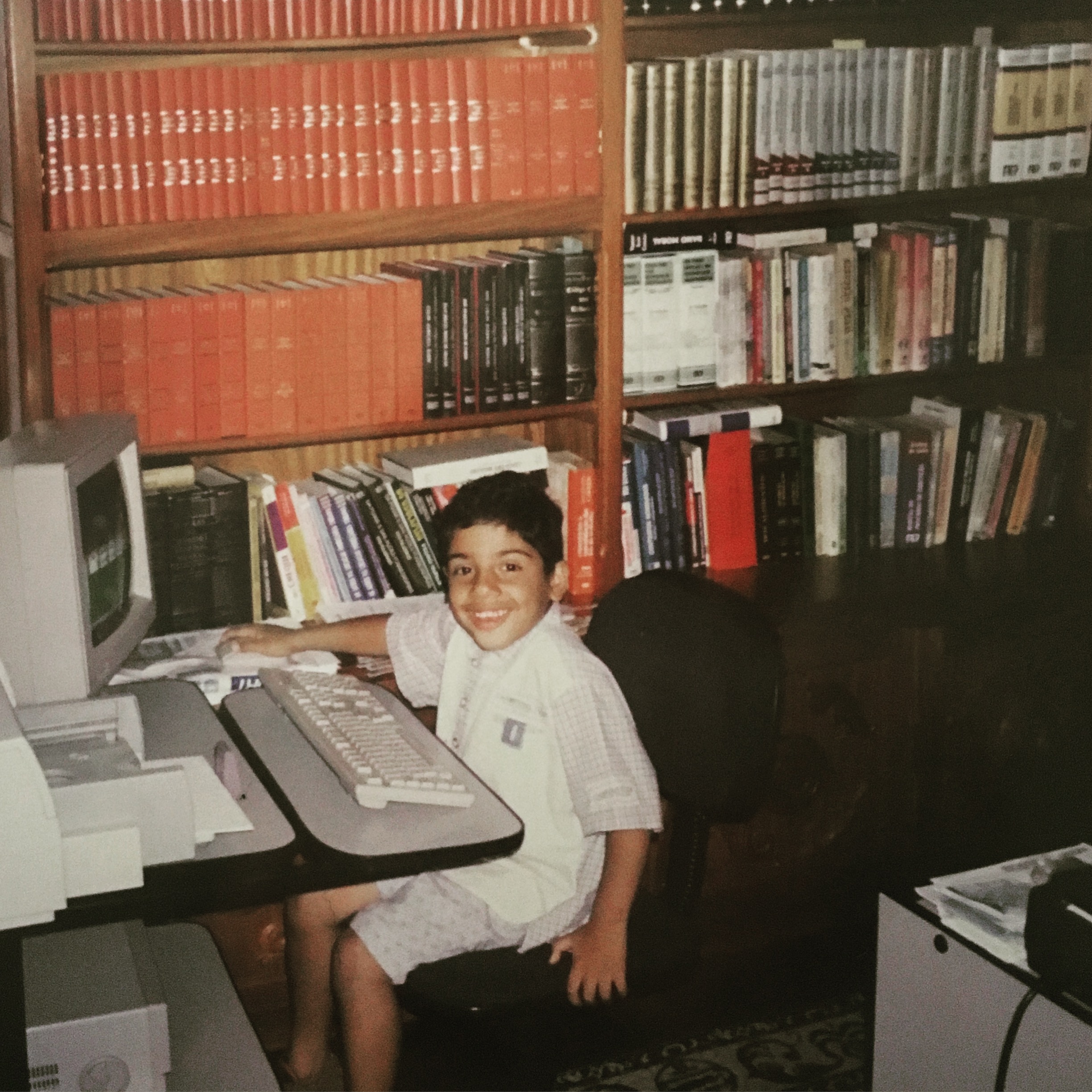 Guilherme Ronchi criança em frente a um computador no escritório do pai